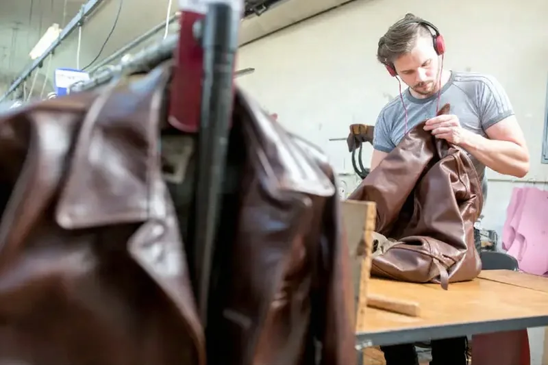 Expert inspecting a finished leather jacket for stitching, fit, and final detailing before approval