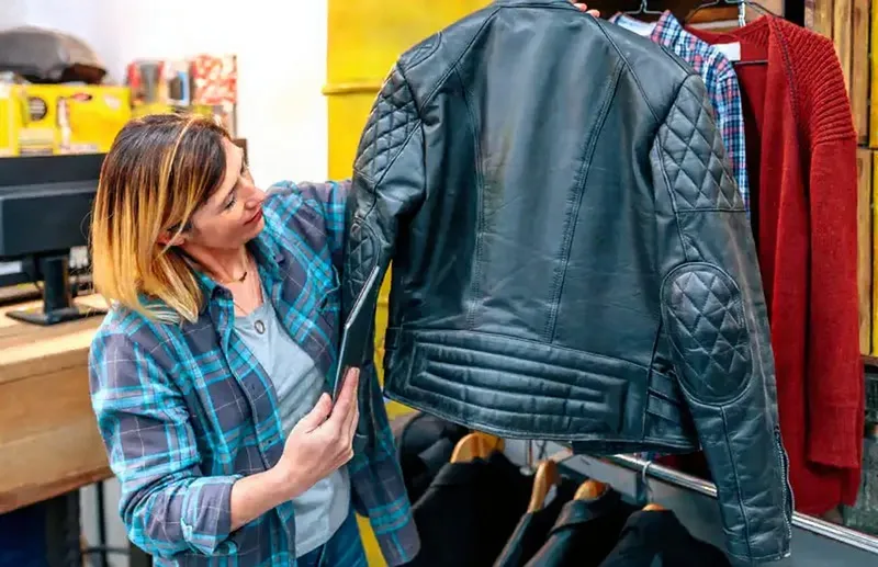 Young woman looking at a leather jacket, symbolizing future trends in style and craftsmanship